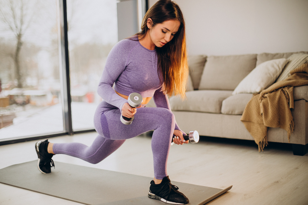 Fit girl doing a lunge exercise at home